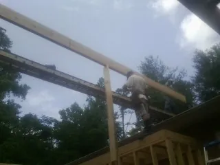 Carpenter setting a ridge beam over a new addition frame — Ice Dam Removal by Roofing Brothers in Berkshire
