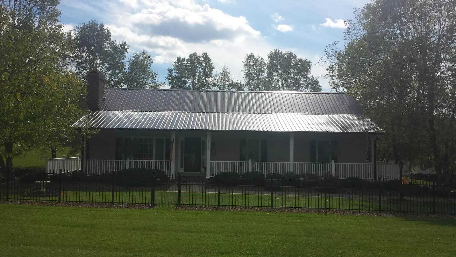 Gray metal roof on a brick ranch with a full width front porch — Gutter Guard Installation work by our crew in Berkshire