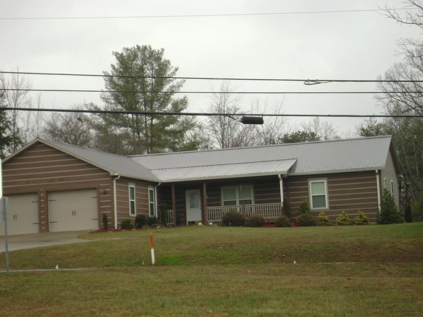 Gray metal roof on a log sided ranch home with a front porch in Berkshire