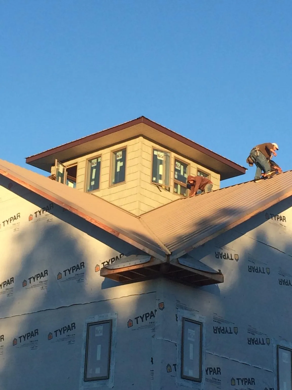 Roofers working around a rooftop cupola on a new metal roof at sunset — Roof Waterproofing in Berkshire by Roofing Brothers